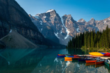 A Row Of Canoes Sitting In The Evening Sun, Ready To Be Taken On The Water. Louise Lake In Banff National Park, Alberta, Canada