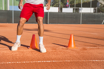 Professional tennis player warming up by dodging cones in zigzag manner.  