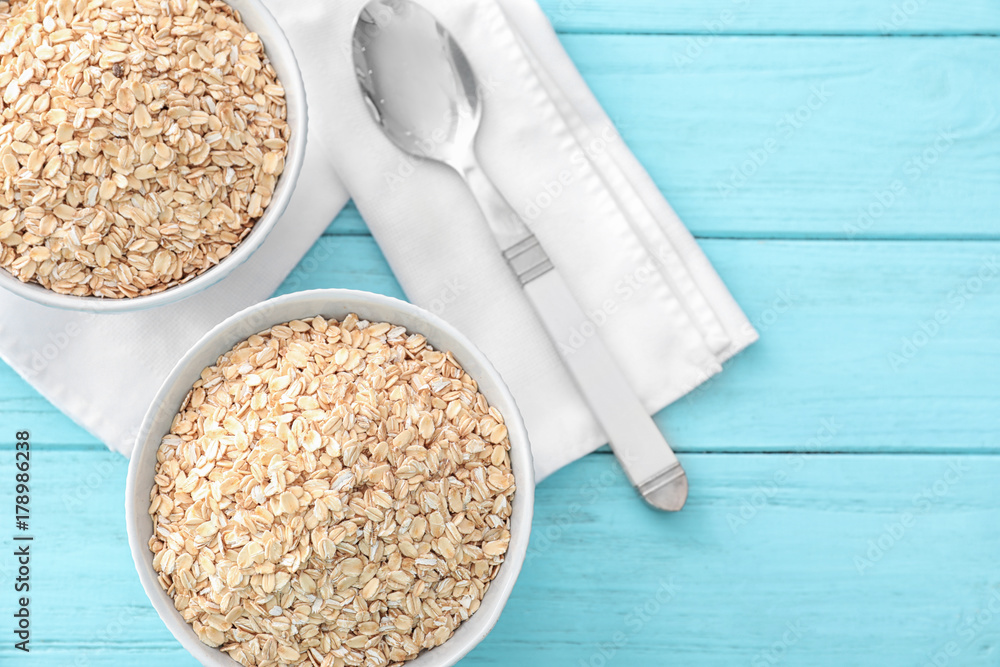 Bowls with raw oatmeal on table
