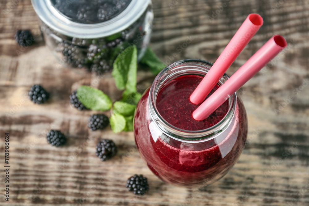 Delicious blackberry smoothie in glass jar on wooden table