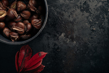 Pile of sweet roasted chestnuts on dark black rustic background. Traditional Christmas snack. Top view, copy space.