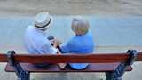 Fototapeta  - Pair of older people sitting on bench.