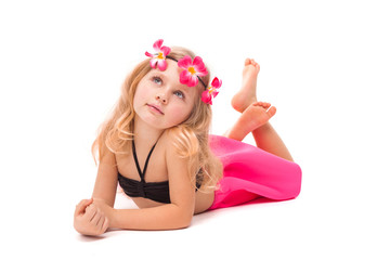 Cute pretty little girl in black bikini, pink skirt and pink wreath, lies