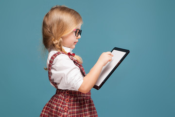 Wall Mural - Cute little girl in red dress, white shirt and glasses holds empty tablet