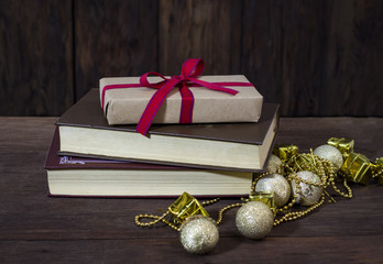 A box with a gift, two books, gold decorative boxes, balls and beads. Focus on the gift box