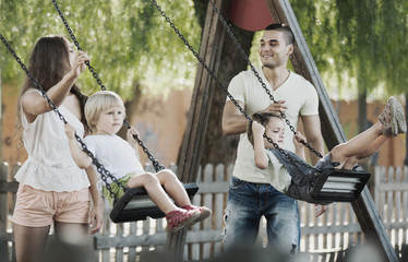 Wall Mural - Smiling parents swinging children