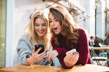 Two Excited Young Girls Using Mobile Phones