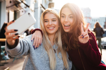 Wall Mural - Two joyful cheerful girls taking a selfie