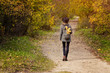 © somemeans - Girl in a hat with a backpack is walking in the autumn forest. Back view