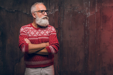 Beautiful senior bearded man in Christmas sweater looking away. Santa Claus wishes Merry Christmas