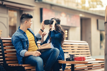 Excited couple using the oculus VR headset with 3d 360 virtual reality, trying to reach for the virtual object. Modern couple using glasses for gaming and Augmented Virtual 360 video simulator