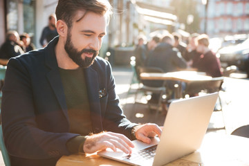 Wall Mural - Portrait of a young stylish man working on laptop computer