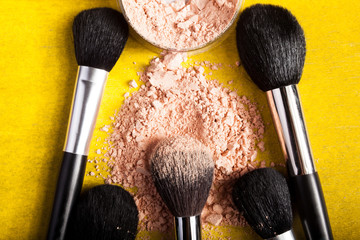 Wall Mural - Different type of make up brushes and spread powder on yellow paper background