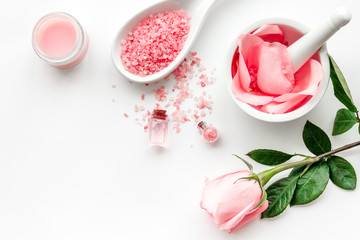 Make cosmetics with rose  oil. Mortar with rose petals and pestle on white background top view copyspace