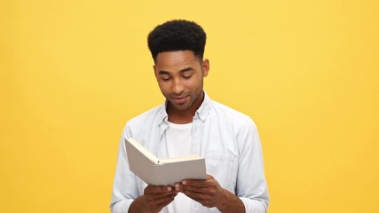 Sticker - Happy african man in shirt holding and reading book over yellow background