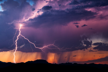 Wall Mural - lightning illuminates a thunderstorm at sunset
