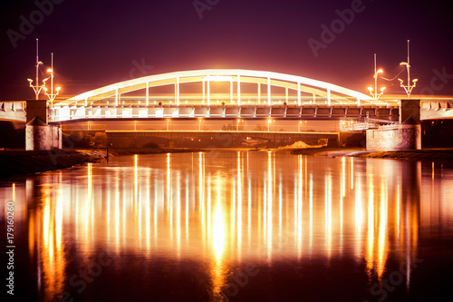 Zdjęcie XXL Nocny widok na most nad rzeką Wartą w Poznaniu, Piękne światła i odbicia w spokojnej wodzie. Wielkopolska.