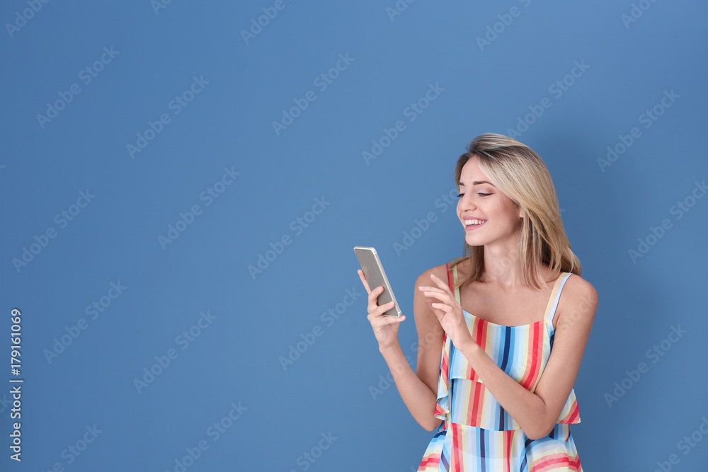 Beautiful young woman with mobile phone on color background