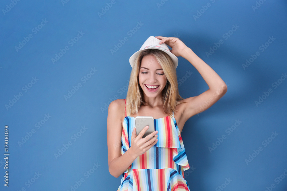 Beautiful young woman with mobile phone on color background