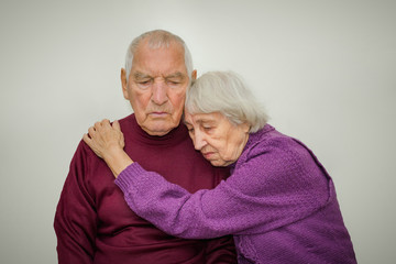 Sad elderly couple on a gray background