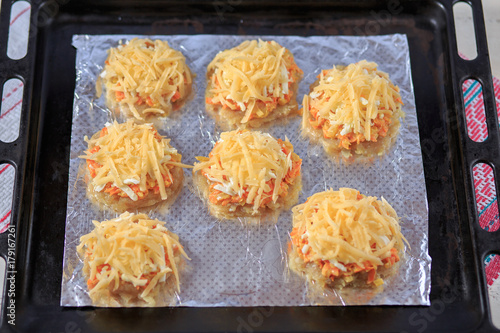 Valokuva Meat crude cutlet with carrots and cheese on a foil on a baking sheet