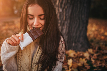 Beautiful young brunette sitting on a fallen autumn leaves in a park,