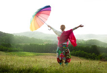Woman With Colorful Umbrella Enjoying Rain In The Meadow.