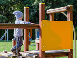 Fototapeta  - Mały chłopiec bawi się na placu zabaw w jesienny słoneczny dzień.