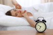 © rogerphoto - Beautiful sleeping woman resting in bed and trying to wake up with alarm clock