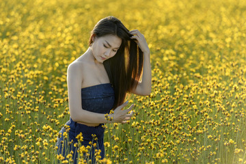 Asian women standing  in a beautiful yellow flower field.