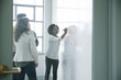 © John Fedele/Blend Images - Businesswoman writing on whiteboard in meeting