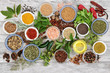© marilyn barbone - Spice and herb seasoning with fresh and dried herbs and spices, including chili pepper selection, mustard powder and seeds, ground and whole peppercorns and olive oil on rustic wood. Top view.