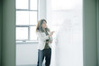 © John Fedele/Blend Images - Caucasian businesswoman holding digital tablet and writing on whiteboard