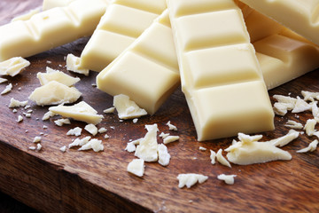 white chocolate bars and white choco pieces on wood.