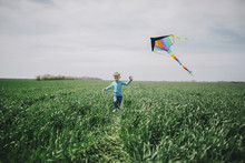Caucasian Boy Flying Kite In Field