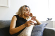 © Julien McRoberts/Blend Images - Mixed race woman laying on sofa holding cell phone