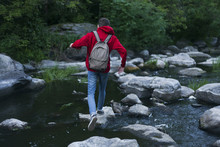 Caucasian Man Walking On Rocks Crossing River