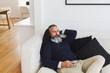 © Strauss/Curtis/Blend Images - Caucasian man on sofa listening to cell phone with headphones