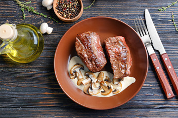 Plate with steak Diane on wooden table