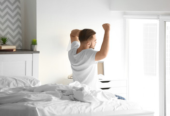 Wall Mural - Morning of handsome young man sitting on bed at home