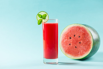 Wall Mural - Glass of healthy watermelon juice in summertime on blue background.