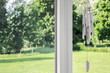 white wooden wind chime on window with green garden	