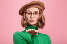 Studio Shot Of Attractive Gorgeous Woman In Spectacles Blows Sweet Kiss At Camera, Flirts With Boyfriend, Says Goodbye. Adorable Female Sends Kiss To You. People, Farewell, Relationship Concept