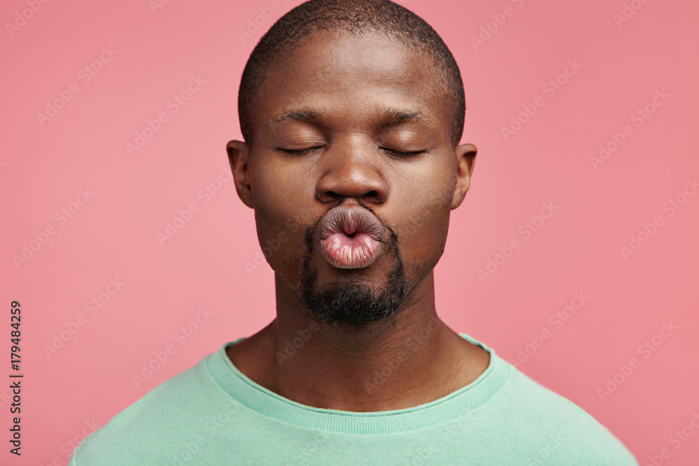 Horizontal portrait of dark skinned man roundes lips as going to