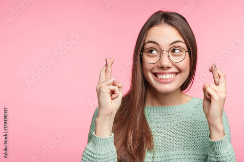 Indoor shot of glad brunette woman wears spectacles, smiles broadly, keeps finge Poster Mural XXL