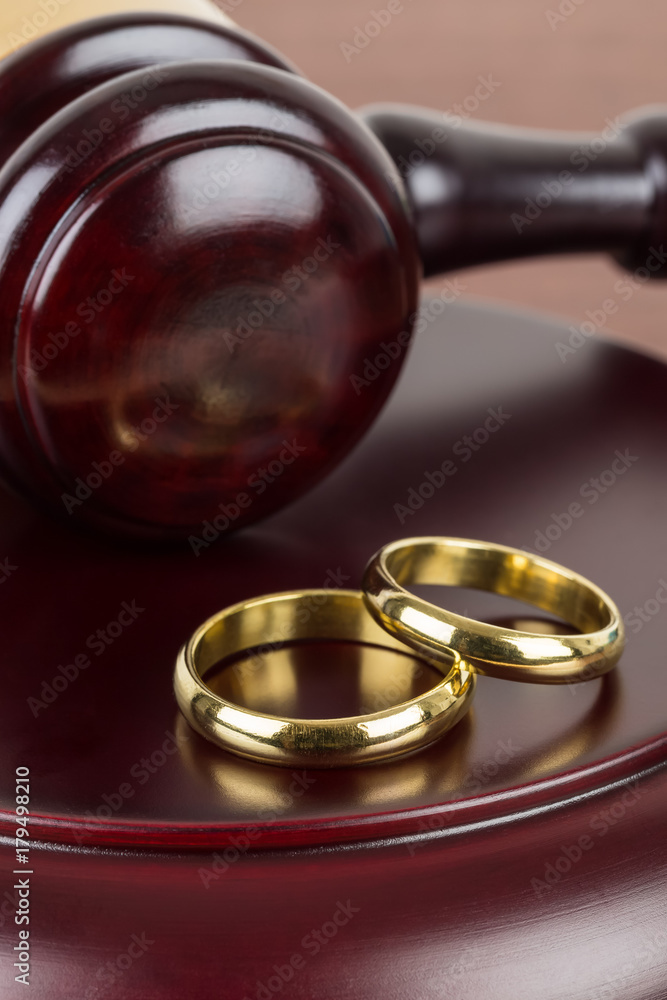 Wooden judge gavel and golden rings divorce concept