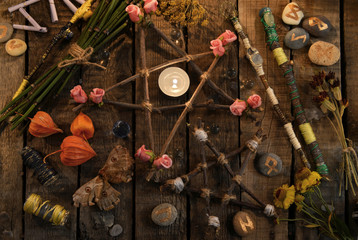 Pentagrams with magic wands, moth, runes and flowers on witch table, top view