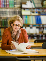 Wall Mural - Senior woman reading book in library