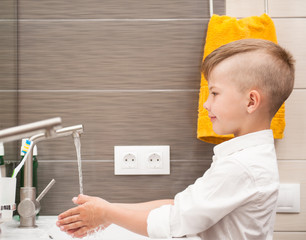 Boy is washing his hands in the bathroom