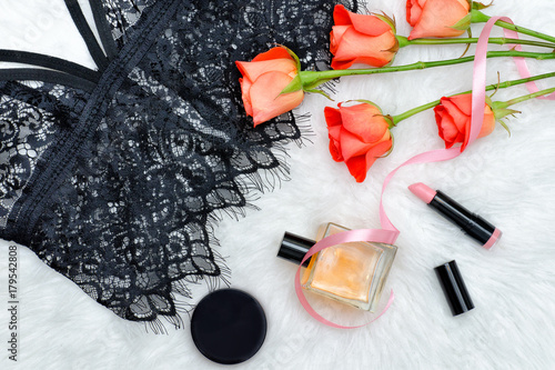 Plakat Czarny top z koronką na białym futerku i pomarańczowych różach oraz kosmetyku. Modna koncepcja.